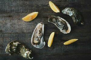 detailopname van vers Open rauw oesters met citroen en ijs Aan een houten achtergrond. gezond zeevruchten. visie van bovenstaande. kopiëren ruimte. zeevruchten. fijnproever voedsel. foto