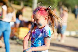 kind in groen kleuren holi. holi gelaats schot Aan voorjaar kleur festival van holi. holi viering concept. de portret lacht de meisje Bij verf partij foto