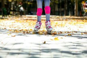 weinig meisje Aan rol skates en tram bescherming rijden in de herfst park. gezond levensstijl concept. foto