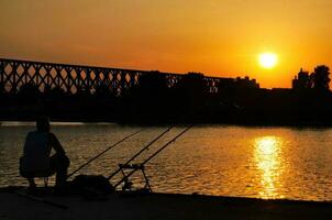 Mens visvangst over- de zonsondergang foto