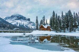 smaragd meer met houten lodge gloeiend en sneeuwval in pijnboom Woud Aan winter Bij yoho nationaal park foto