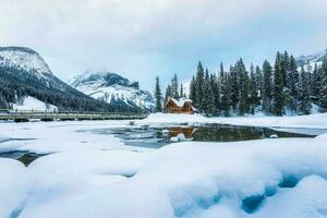 bevroren smaragd meer met houten lodge in pijnboom Woud Aan winter foto