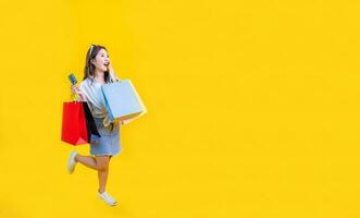 mooi Aziatisch vrouw in modieus zomer mode is glimlachen en Holding boodschappen doen zak in geluk voor korting uitverkoop geïsoleerd Aan geel achtergrond voor reclame en Promotie evenement concept foto