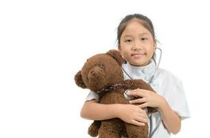 kind in dokter jas gebruik makend van stethoscoop onderzoeken teddy beer foto