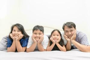 Aziatisch gelukkig jong familie aan het liegen in bed samen foto