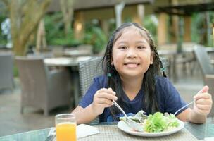 Aziatisch schattig meisje genieten naar eten vegetarisch salade foto