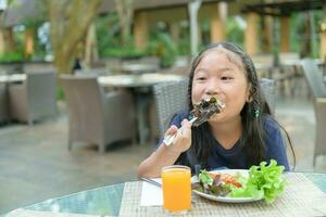 Aziatisch schattig meisje genieten naar eten vegetarisch salade foto