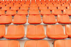 rijen van leeg oranje plastic tribune stoelen Bij stadion. foto