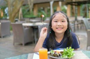 Aziatisch kind genieten naar eten vegetarisch salade foto