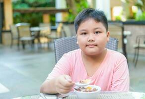 zwaarlijvig dik jongen aan het eten ontbijtgranen met de melk foto