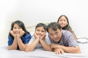Aziatisch gelukkig jong familie aan het liegen in bed samen foto