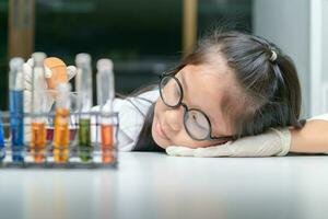 schattig weinig meisje vervelend bril en laboratorium jas maken experiment foto
