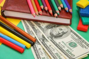 pennen, gekleurde potloden, plasticine, boek, honderd dollar rekeningen foto