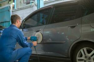 Kaukasisch Mens is gebruik makend van auto polijsten machine in reparatie monteur schilderij winkel foto