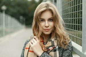 portret van een mooi jong blond vrouw in herfst wijnoogst sjaal in de buurt metaal rooster foto