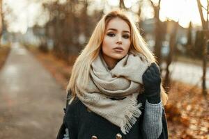 mooi jong blond vrouw in jas en sjaal Aan de achtergrond van herfst park. foto