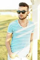 knap Mens in een elegant zomer t-shirt resting Aan de strand. foto