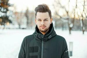 knap Mens met een baard en kapsel in winter jasje in de park foto