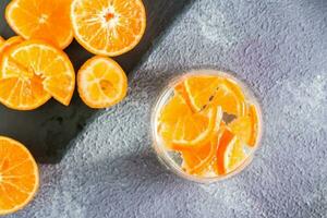 niet alcoholisch cocktail mineraal water met stukken van mandarijnen in een glas en rijp fruit De volgende naar Aan de tafel. ontgiften voedsel. top visie foto