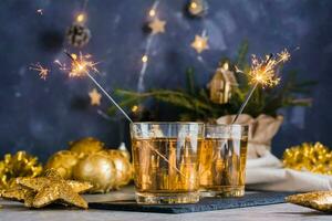 twee bril met wit wijn en brandend sterretjes Aan de Kerstmis tafel. goud palet foto