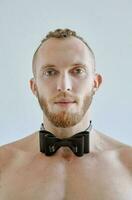 portret van knap Kaukasisch atletisch jong Mens topless in leer boog binden. fitheid, bodybilding foto