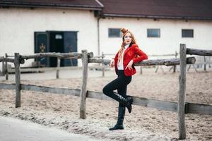 roodharig jockeymeisje in een rood vest en zwarte hoge laarzen foto