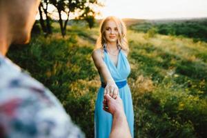 blond meisje met losse haren in een lichtblauwe jurk en een jongen in het licht van de zonsondergang foto