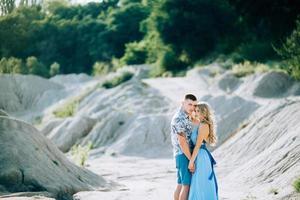 blond meisje in een lichtblauwe jurk en een man in een licht overhemd in een granietgroeve foto