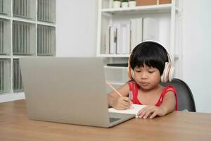 gelukkig Aziatisch meisje leerling online aan het leren klasse van een computer met een docent, online onderwijs is een technologie voor sociaal afstand in een nieuw normaal levensstijl, concept van huis school- en tutor foto