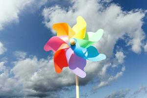 kleurrijk pin wiel of wind wiel met bewolkt lucht foto