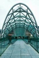 mensen wandelen langs de brug van vrede. de modern architectuur en beroemd mijlpaal in tbilisi Georgië. foto