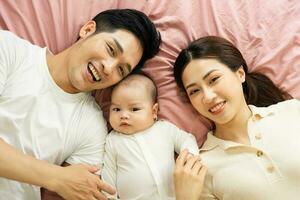 Aziatisch familie beeld met baby aan het liegen in bed foto