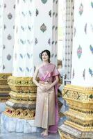 mooi Aziatisch meisje in Thais traditioneel kostuum Bij tempel foto