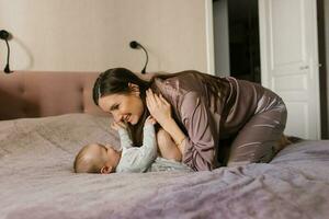 gelukkig moeder hebben pret en lachend met haar baby Aan de bed foto