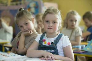 kleuters Bij school- bureaus in kleuterschool. foto