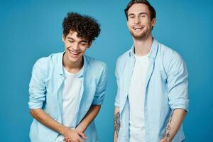 jong jongens in de dezelfde overhemden en t-shirts zijn gebaren met hun handen Aan een blauw achtergrond vrienden foto