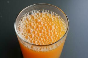 glas van oranje sap met bubbel Aan tafel foto