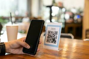 Mens gebruik smartphone naar scannen qr code voor bestellen menu in cafe restaurant met een digitaal levering. Kiezen menu en bestellen accumuleren korting. e portemonnee, technologie, betalen online, credit kaart, bank app. foto