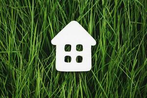 wit papier huis Aan groen gras, duurzame leven en milieuvriendelijk behuizing foto