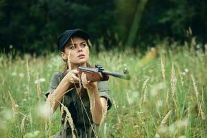 vrouw houdt een wapen in de handen van onderdak in de gras vers lucht groen bladeren foto