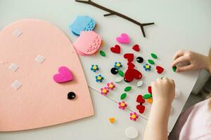 een blogger meisje maakt een voelde ambacht voor Valentijnsdag dag in de vorm van een hart. de concept van kinderen creativiteit en handgemaakt. foto