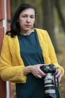 ouderen vrouw in helder kleren met een camera in haar handen. foto