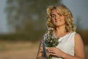 mooi middelbare leeftijd blond met een boeket van wilde bloemen. foto