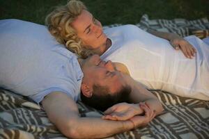 een mooi middelbare leeftijd paar in liefde leugens Aan de gras. een Mens en een vrouw zijn resting in natuur. foto