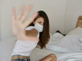 vrouw vervelend medisch masker aan het bedekken haar gezicht met hand- Aan bed binnenshuis coronavirus pandemisch isolatie foto