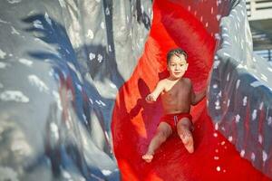 afbeelding van jong jongen spelen in buitenshuis aqua park foto