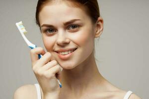 mooi vrouw met een tandenborstel in hand- ochtend- hygiëne licht achtergrond foto
