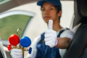 technicus tonen duimen omhoog en Holding toezicht houden op gereedschap naar controleren en gemaakt auto lucht conditioner systeem, klusjesman controleren auto lucht conditioning systeem, lucht conditioning reparatie foto