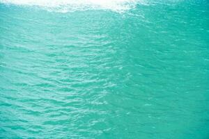 groen water met rimpelingen Aan de oppervlak. onscherp wazig transparant blauw gekleurde Doorzichtig kalmte water oppervlakte structuur met spatten en bubbels. water golven met schijnend patroon structuur achtergrond. foto