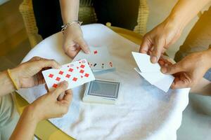 groep van Aziatisch vrienden spelen kaart spellen voor pret in een herberg gedurende hun vrij tijd terwijl op reis samen.zacht en selectief focus. foto